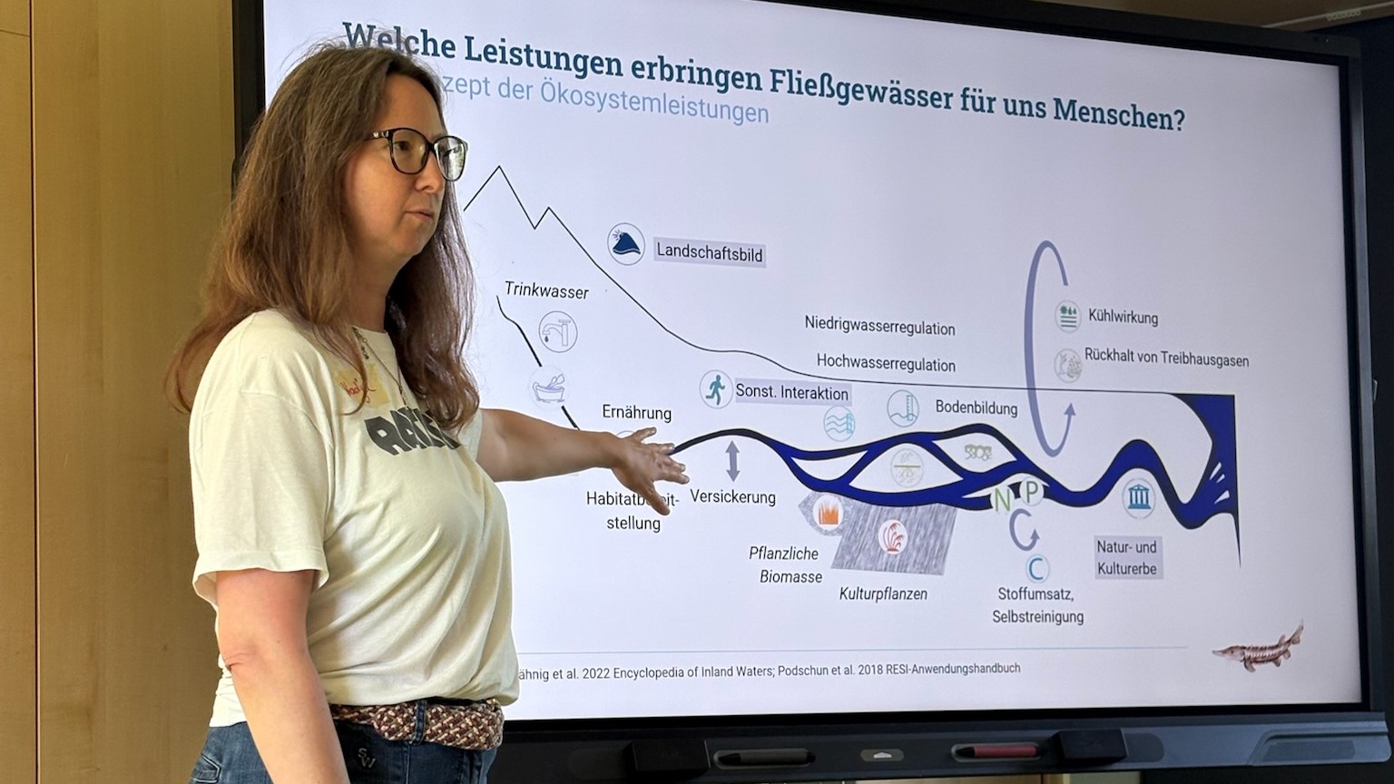 Eine Referentin erklärt die Ökosystemleistungen eines Fließgewässers