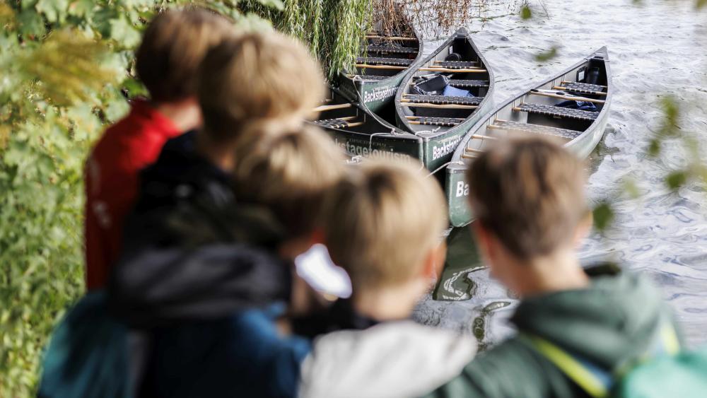 Kinder schauen sich einige Kanus an