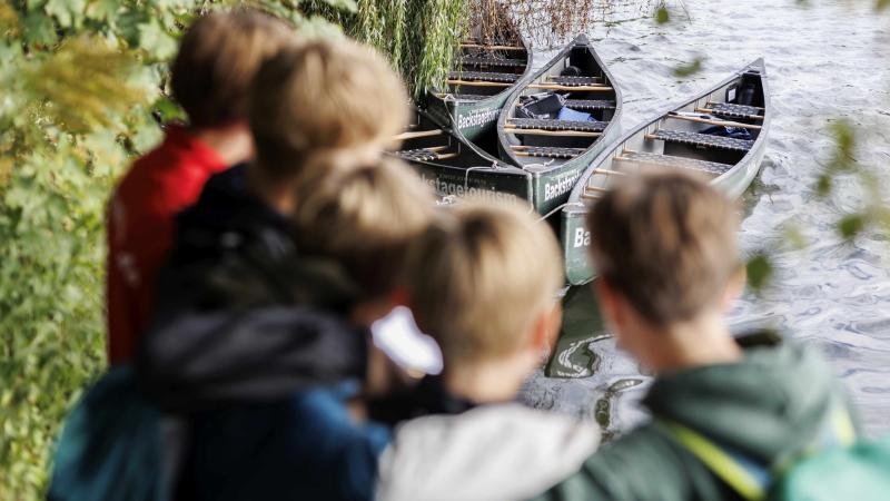 Kinder schauen sich einige Kanus an